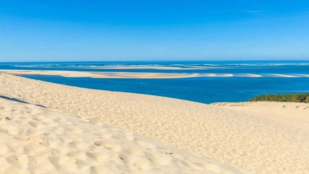 A sandy beach with clear blue waters and distant land.