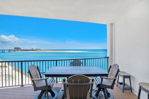 Ein Balkon mit Tisch und Stühlen mit Blick auf Strand und Meer.