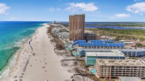 A coastal hotel with multiple buildings, a beach, and a clear view of the ocean.