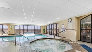 Una piscina interior con jacuzzi, paredes de vidrio transparente y un reloj en la pared.