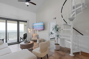 Un vaste espace de vie avec balcon, un escalier moderne et un grand tableau.