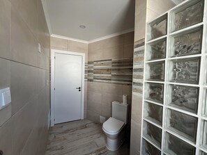 Une petite salle de bain comprenant des toilettes, une porte et un mur orné d’un motif décoratif en carreaux.