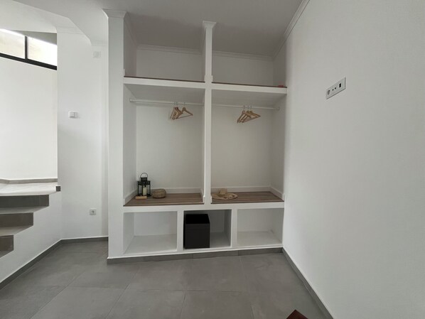Un intérieur blanc avec une étagère intégrée, une petite poubelle et une fenêtre.