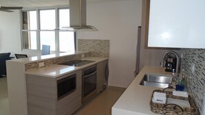 A modern kitchen with a central island, built-in oven, and a stainless steel range hood. - Lucille's Corner (Carolina)