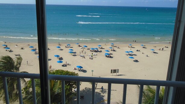 A beach with umbrellas and people, viewed from a balcony. - Lucille's Corner (Carolina)