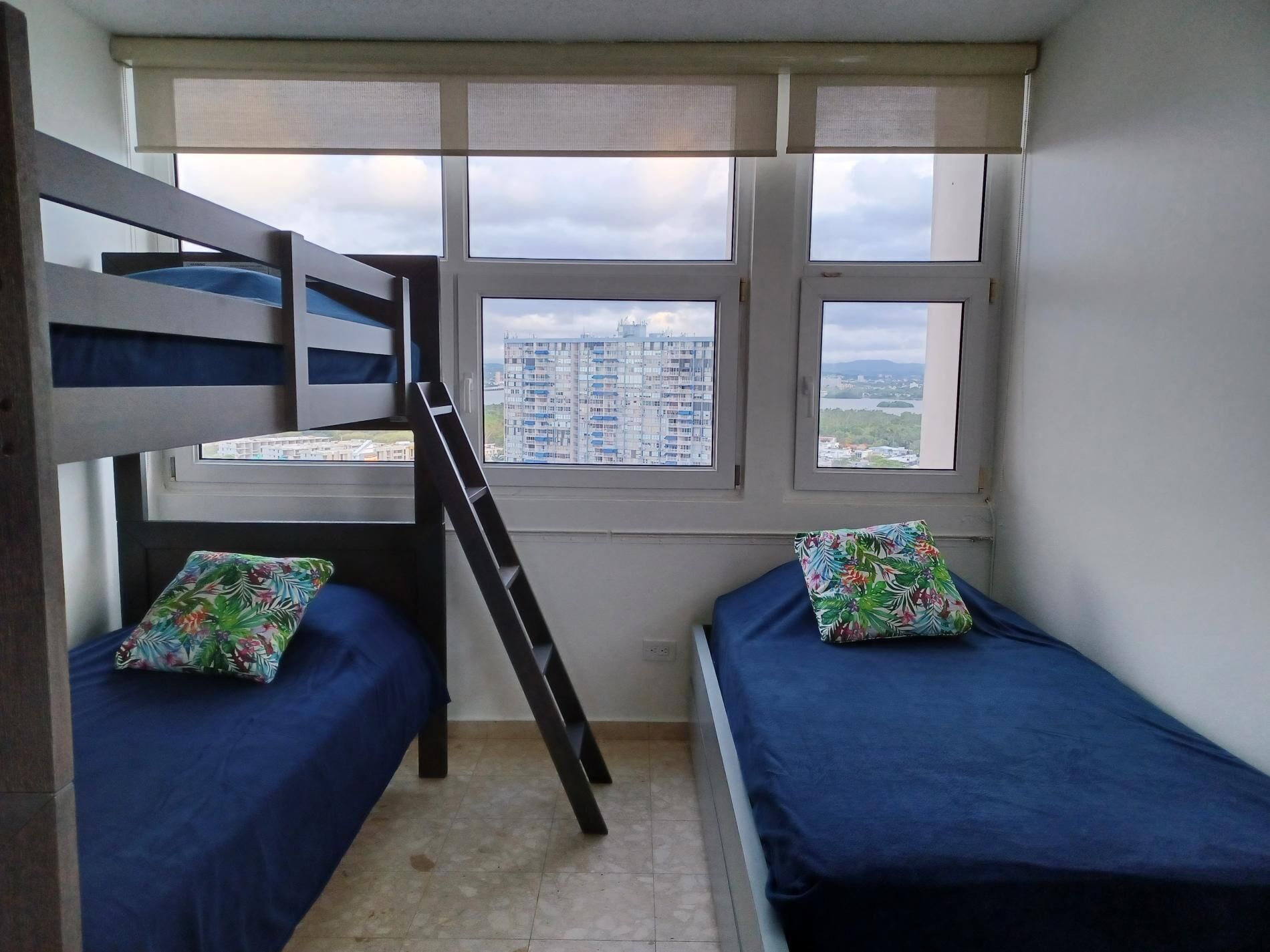 Un dormitorio con dos literas, una escalera y una ventana con vista a la ciudad.