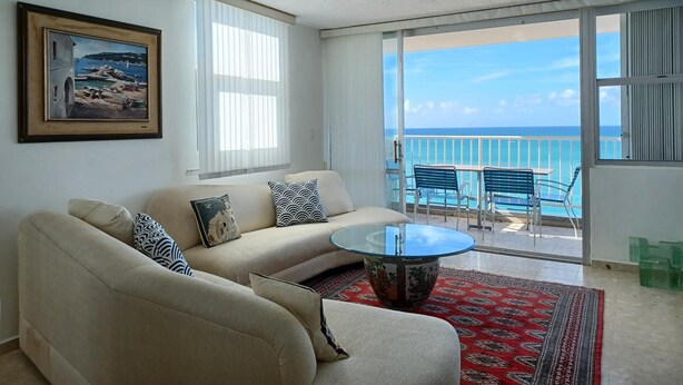 A living room with a sofa, a glass coffee table, and a view of the ocean through large windows. - Lady From Spain (Carolina)