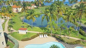 A resort with a swimming pool, palm trees, and a view of the ocean. - Blue Horizon (Humacao)