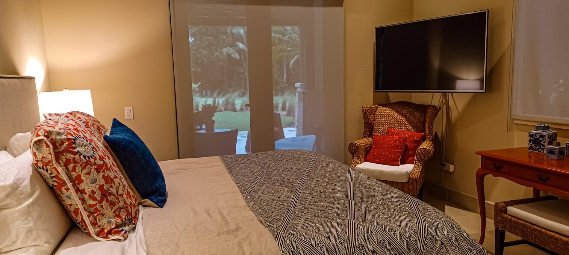 Ein Hotelzimmer mit einem Bett, einem Sessel, einem Fernseher und einer Projektionsleinwand, die eine Außenansicht zeigt.
