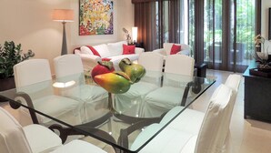 A modern living room with a glass dining table, white sofas, and a large window with curtains. - Orchid Villa (Río Grande)