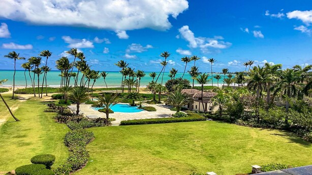 Un complexe hôtelier doté d’une piscine, de palmiers et offrant une vue sur la plage.
