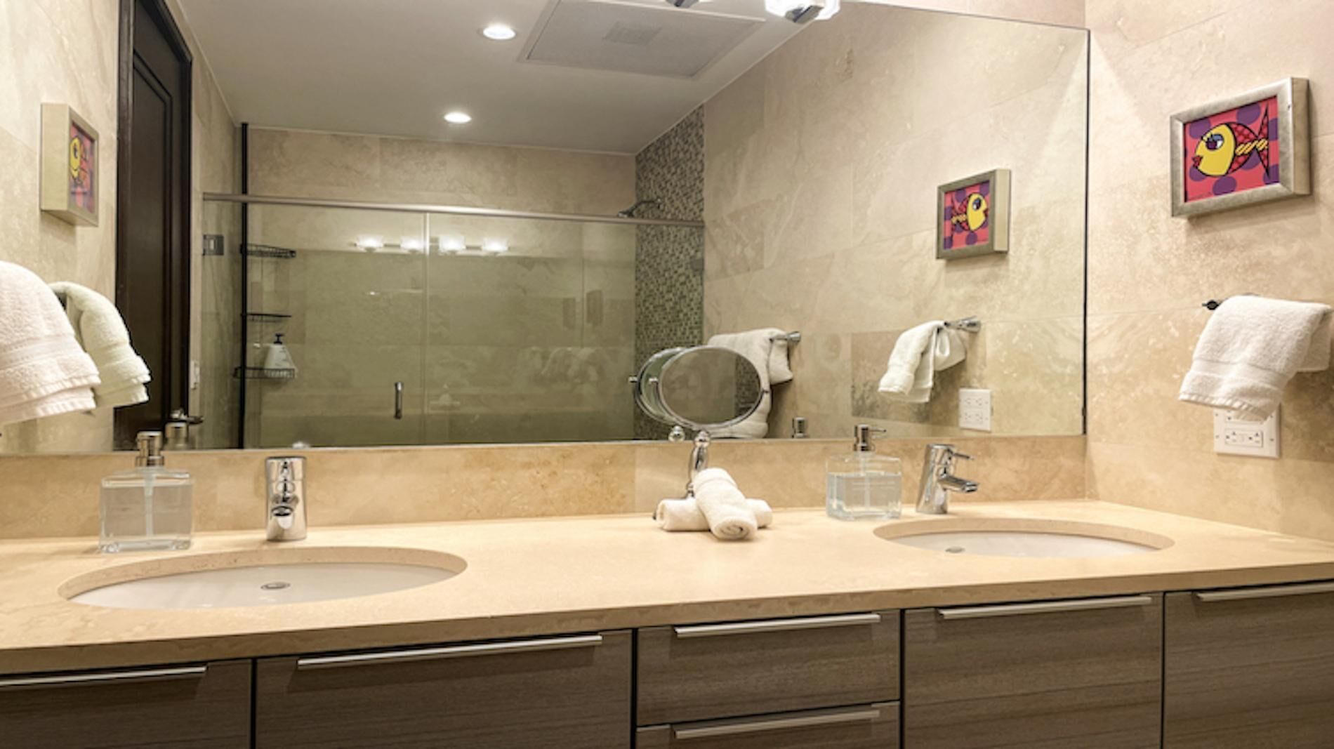 A modern bathroom with two sinks, a large mirror, and a shower.