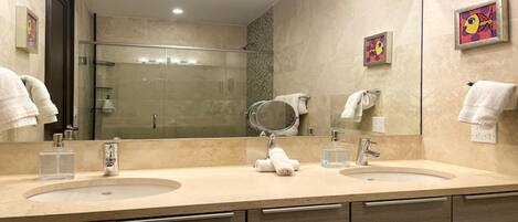 A modern bathroom with two sinks, a large mirror, and a shower.