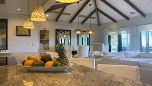 Une cuisine moderne avec un panier de fruits, des meubles blancs et des luminaires suspendus.