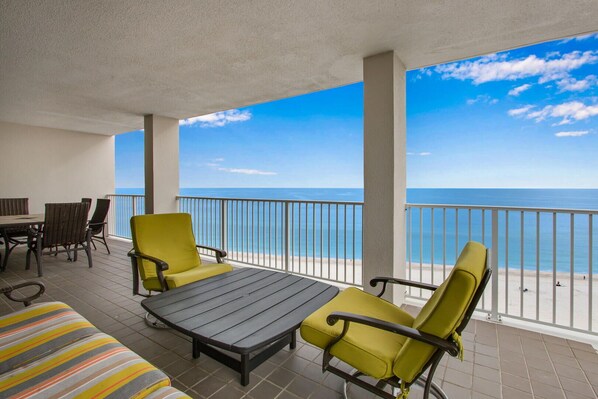 Een balkon met een tafel en stoelen, met uitzicht op een strand.