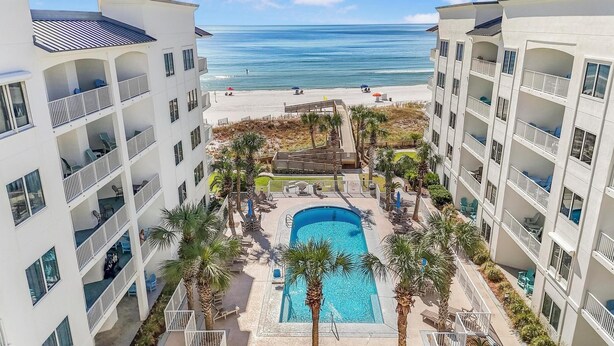 A resort with a central pool, multiple balconies, and a beach view. - ⭐Outdoor Pool | Gulf and Pool Views | Palm Beach A23⭐ (Orange Beach)