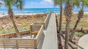 A wooden boardwalk leading to a beach with palm trees and a clear view of the ocean. - ⭐Outdoor Pool | Gulf and Pool Views | Palm Beach A23⭐ (Orange Beach)
