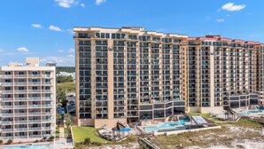 A high-rise hotel with multiple balconies, a swimming pool, and a well-maintained lawn area. - 🌞Beachfront Bliss | Gulf Views | Amazing Amenities | Phoenix I 1097🌞 (Orange Beach)