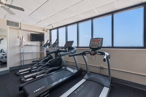 Un gimnasio con cintas de correr, una bicicleta estática y una máquina de remo.