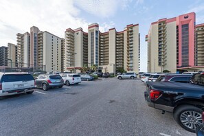 Un parking contenant de nombreux véhicules, entouré d’immeubles de grande hauteur dotés de balcons.