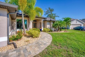Stunning home with a beautifully manicured lawn and lush landscaping, featuring a garage and driveway.