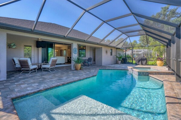 Relax by the pool, surrounded by comfortable seating and a door leading to an adjacent room.