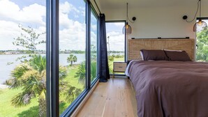 A bedroom with a large window, a bed, a nightstand, and a hanging light fixture. - A Luxury Bayfront Retreat with a Resort-Style Pool & Private Dock (Panama City)