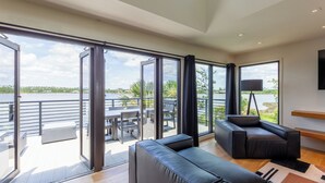 A spacious living area with a large sliding glass door leading to a balcony overlooking a body of water. - A Luxury Bayfront Retreat with a Resort-Style Pool & Private Dock (Panama City)