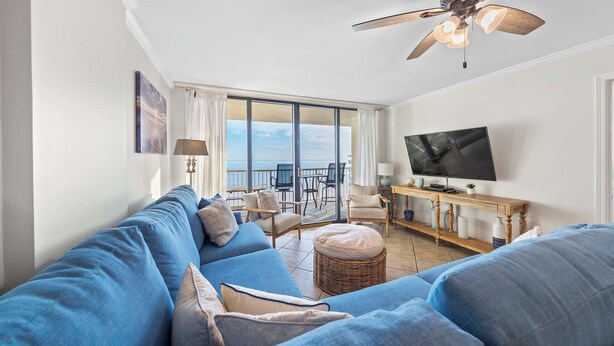 Una sala de estar con sofá azul, televisor y balcón con vistas.