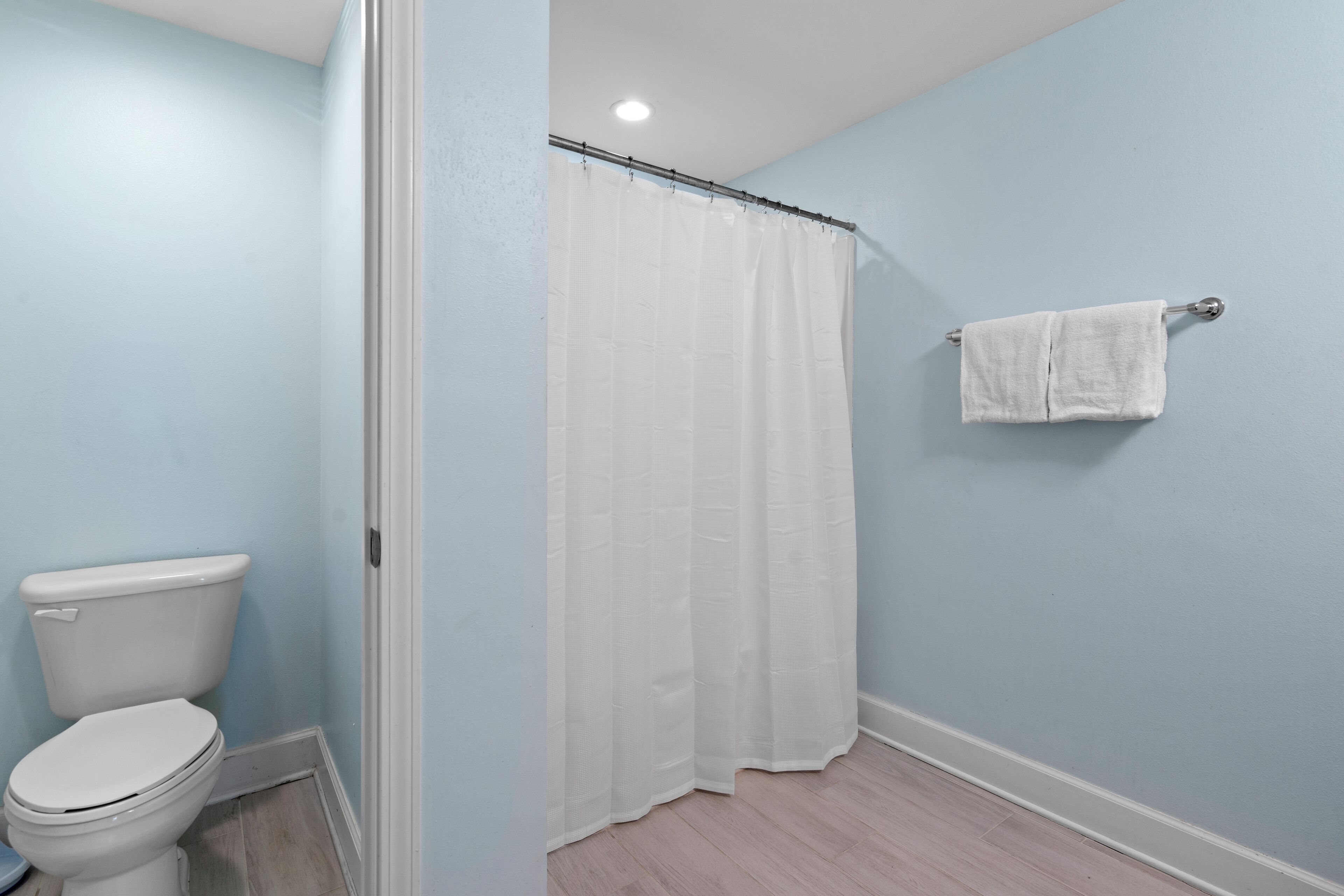 Un baño con inodoro, cortina de ducha y barra para toallas.