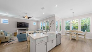 A modern kitchen with a central island, a dining area with a wooden table, and a living room with a sofa and TV. - ⭐Fabulous Amenities | Close to Beach | Summer Salt 24181⭐ (Orange Beach)