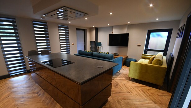 A modern living room with a herringbone wood floor, a central island, a sofa, and a yellow armchair. - Luxury 2 bedroom-Fully Accessible ground floor property. Norfolk, Attleborough. (Attleborough)