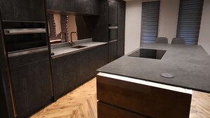 A modern kitchen with dark cabinetry, a central island, and a built-in oven. - Luxury 2 bedroom-Fully Accessible ground floor property. Norfolk, Attleborough. (Attleborough)