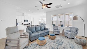 A modern living room with a grey sofa, blue armchairs, and a dining area in the background.