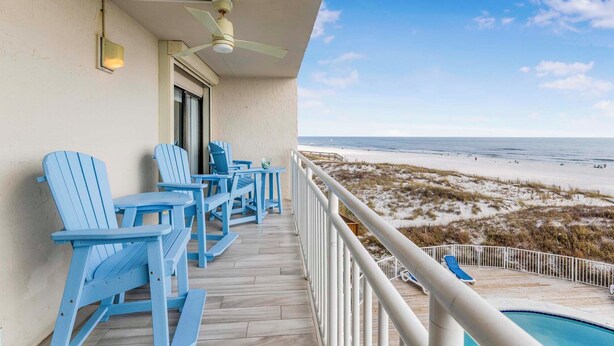 A balcony with blue Adirondack chairs and a pool.