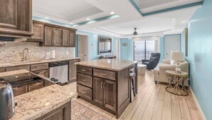 A modern kitchen with granite countertops, dark wooden cabinets, and a central island.