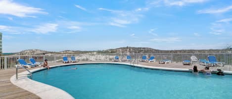 A pool with blue chairs and a wooden deck.