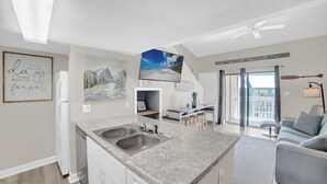 A modern kitchen with granite countertops, a double sink, and a dining area with a bar stool.