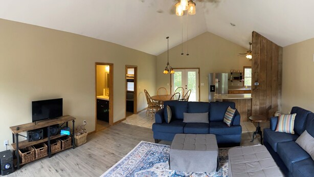 A spacious living area with a large blue sofa, a television, and a wooden entertainment unit.