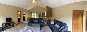 A spacious living area with a large blue sofa, a television, and a wooden entertainment unit. - 3-bedroom family friendly home on 4 acres near Hermann with WiFi, AC, deck (Hermann)