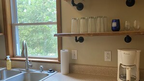 A kitchen with a stainless steel sink, a coffee maker, and a dish drying rack.