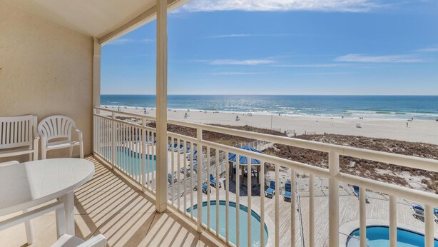 Un balcon avec piscine, vue sur la plage et espace salon extérieur.