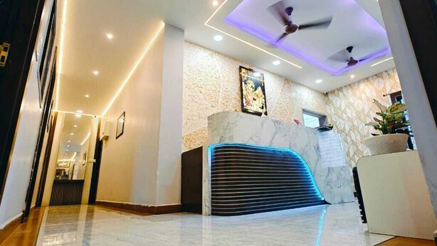 A reception area with a marble reception desk, a ceiling fan, and a wall-mounted television. - hotel basurivala  (Bhopal)