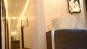 A hotel lobby with a marble reception desk, a framed artwork on the wall, and a tiled floor. - hotel basurivala  (Bhopal)