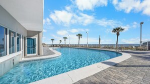 Una piscina con agua cristalina azul, rodeada por un solado empedrado y palmeras.
