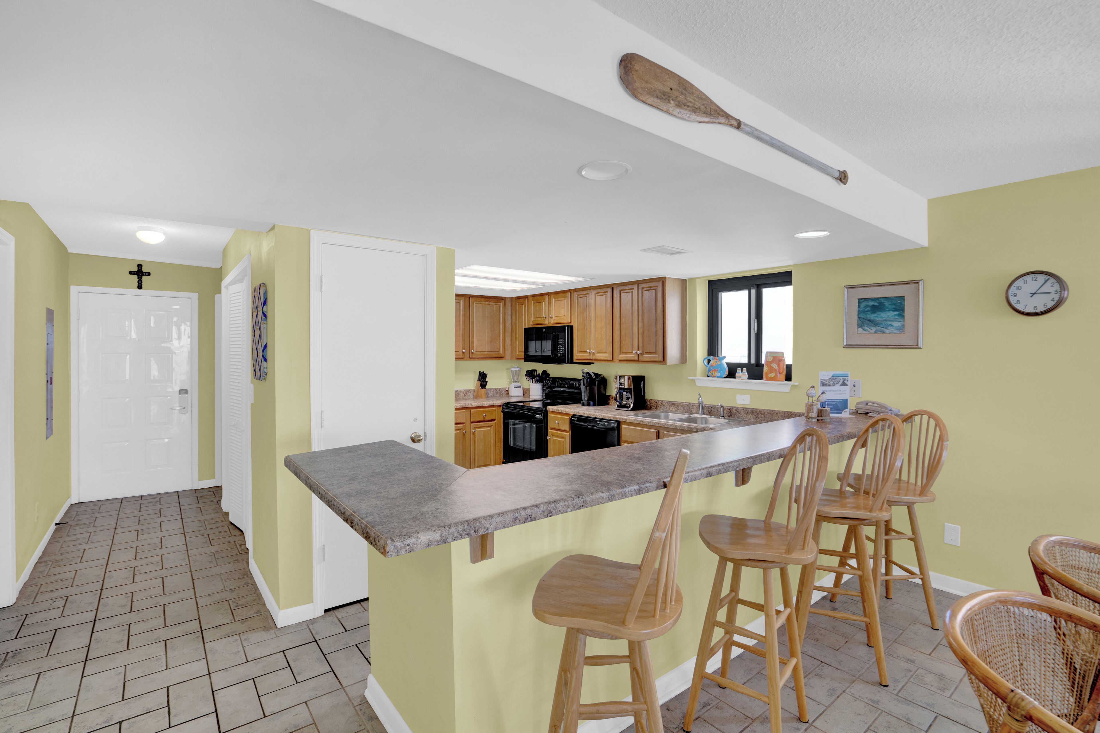 A kitchen with wooden cabinets, a granite countertop, and a bar area with bar stools.