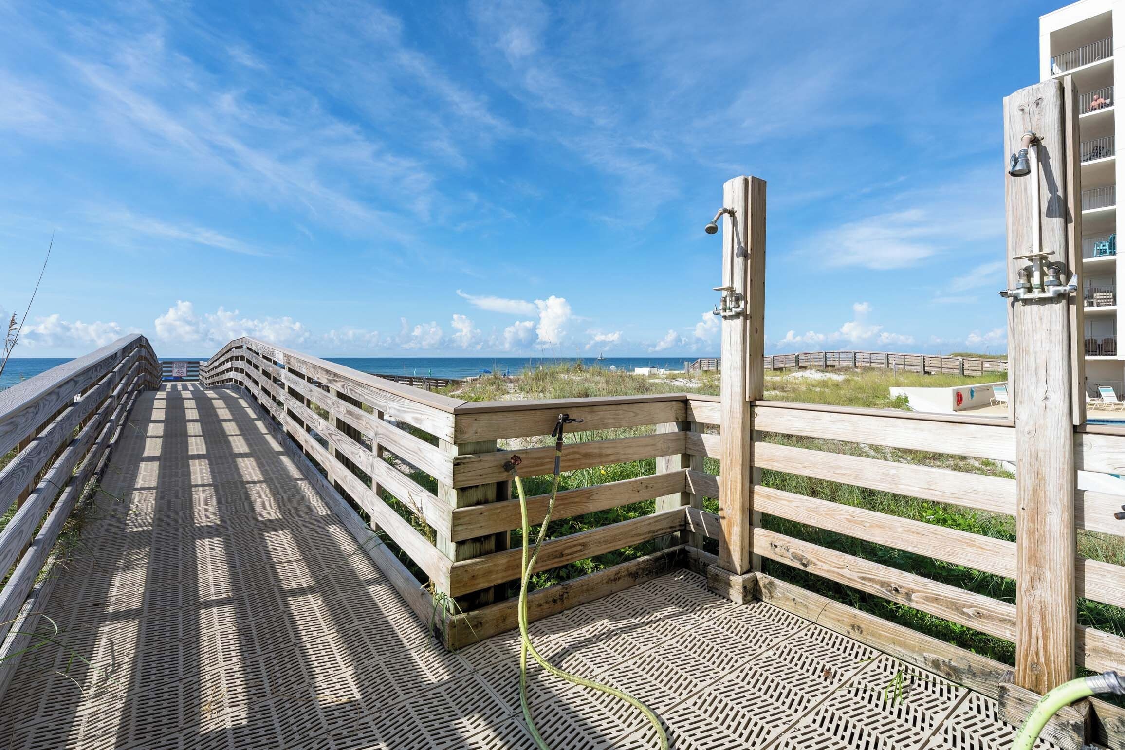 A wooden boardwalk leading to a beach with a clear sky.