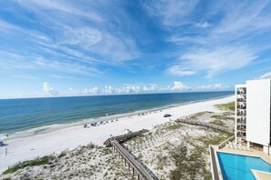 A beach view with a wooden boardwalk leading to a pool area, overlooking a sandy beach and the ocean. - ⭐Wind Drift 702E | Gulf Front with Gorgeous Views | Walk to Beach⭐ (Orange Beach)