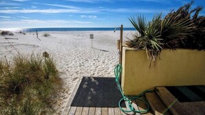 A beach with a wooden deck, a green hose, and a sign.