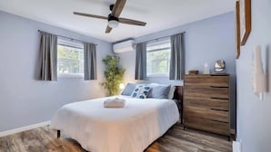 A bedroom with a bed, a ceiling fan, a dresser, and a window with curtains.